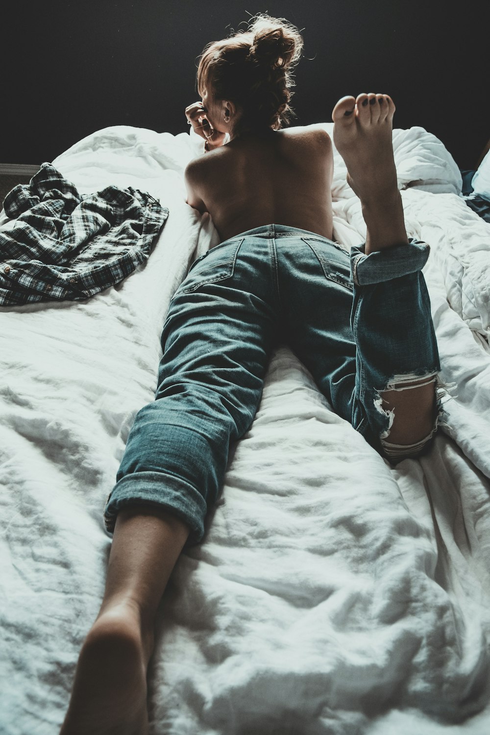 a shirtless man laying on a bed with his feet up