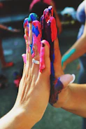 Close-up of hands covered in colorful paint, creating spontaneous art.