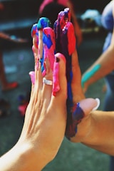 Hands collaborating on a creative art project with colorful materials.