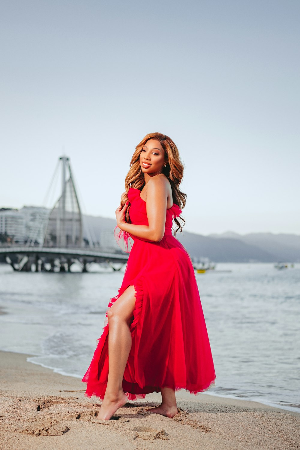 a woman in a red dress standing on a beach