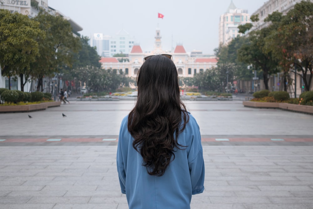 a woman in a blue shirt is standing in a courtyard