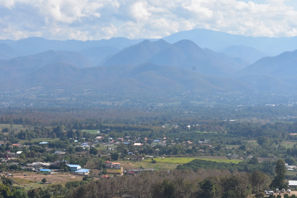 a scenic view of a town with mountains in the background