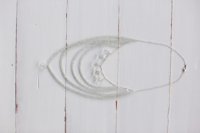 Delicate silver necklaces with intricate designs laid out on a wooden table.