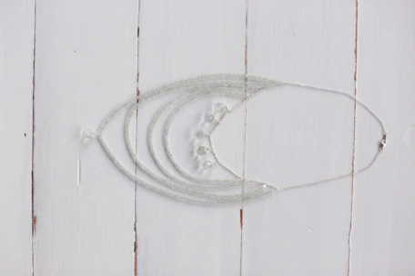 Close-up of a delicate silver necklace with intricate patterns on a rustic wooden table