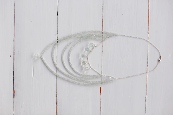 A collection of delicate beads and pearls arranged on a rustic wooden table.