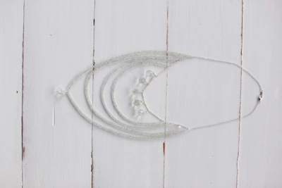 Close-up of a delicate handcrafted silver necklace with intricate floral patterns on a rustic wooden table.