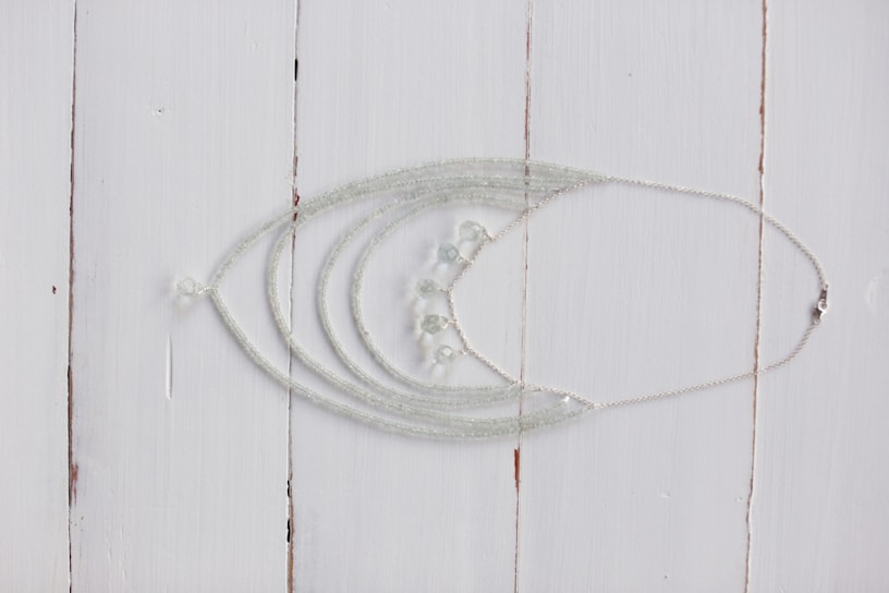 Close-up of a handcrafted silver necklace with intricate Indian motifs displayed on a rustic wooden table.
