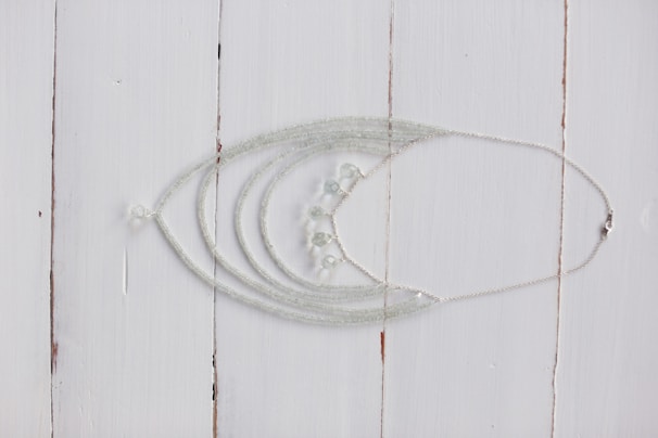 Close-up of a delicate handmade silver necklace with tiny sea-inspired charms on a rustic wooden background