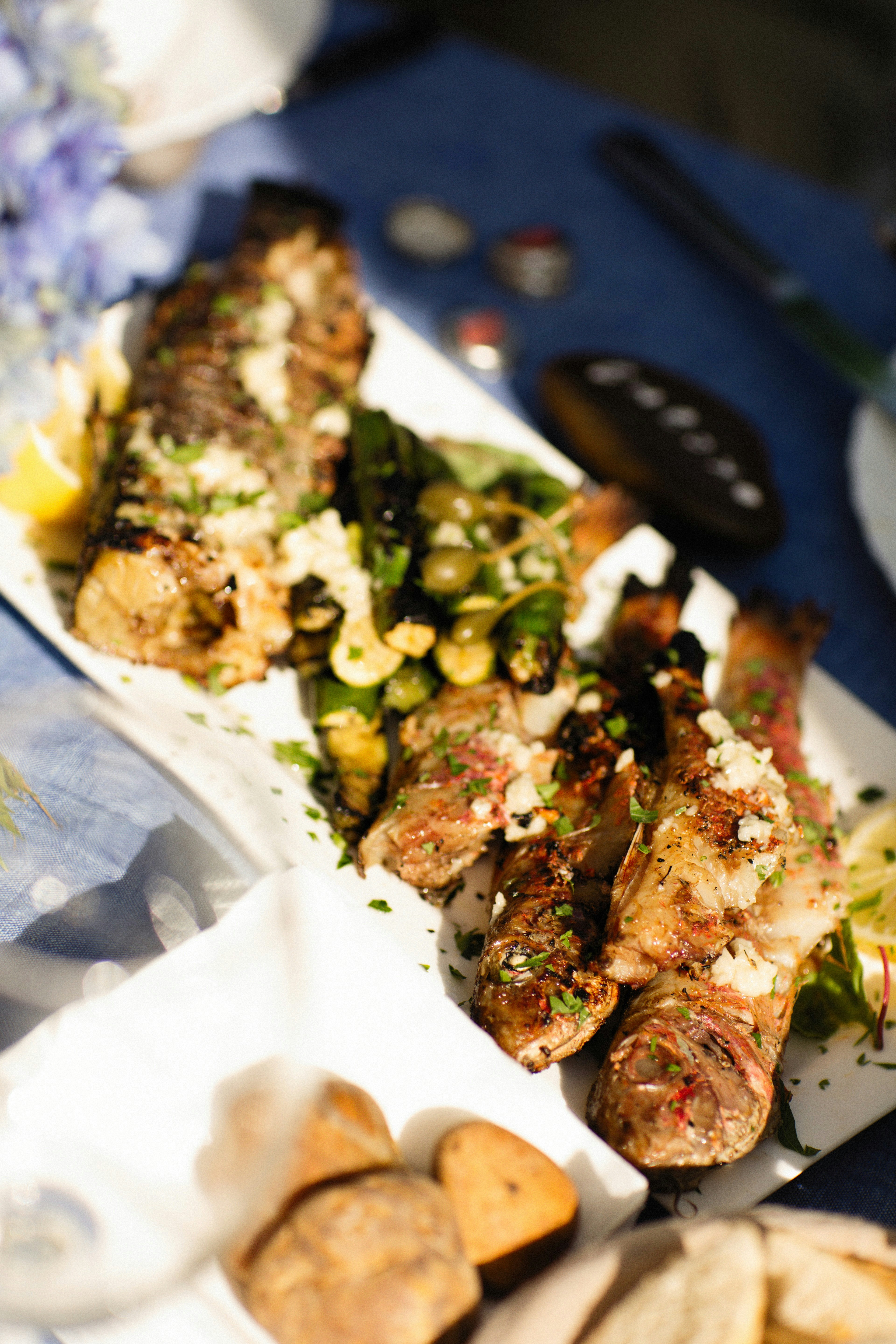 Pesce fritto appena servito su piatto di carta con limone, lungomare ligure azzurro sullo sfondo, folla festosa in lontananza