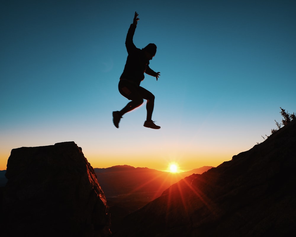 a person jumping in the air over a mountain