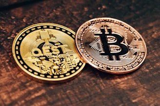 two gold and silver bitcoins sitting on a table