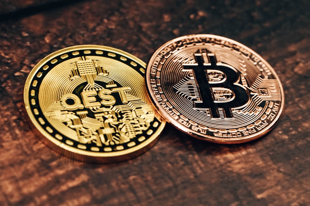 two gold and silver bitcoins sitting on a table