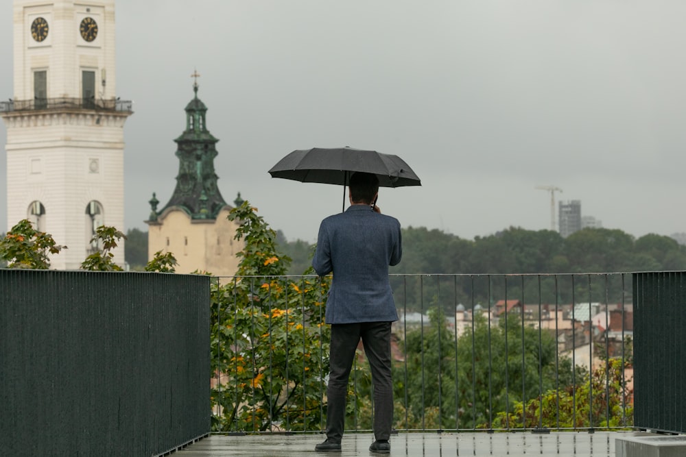 a man holding an umbrella while standing on a bridge