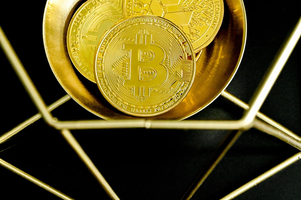 a golden bit coin sitting on top of a metal stand