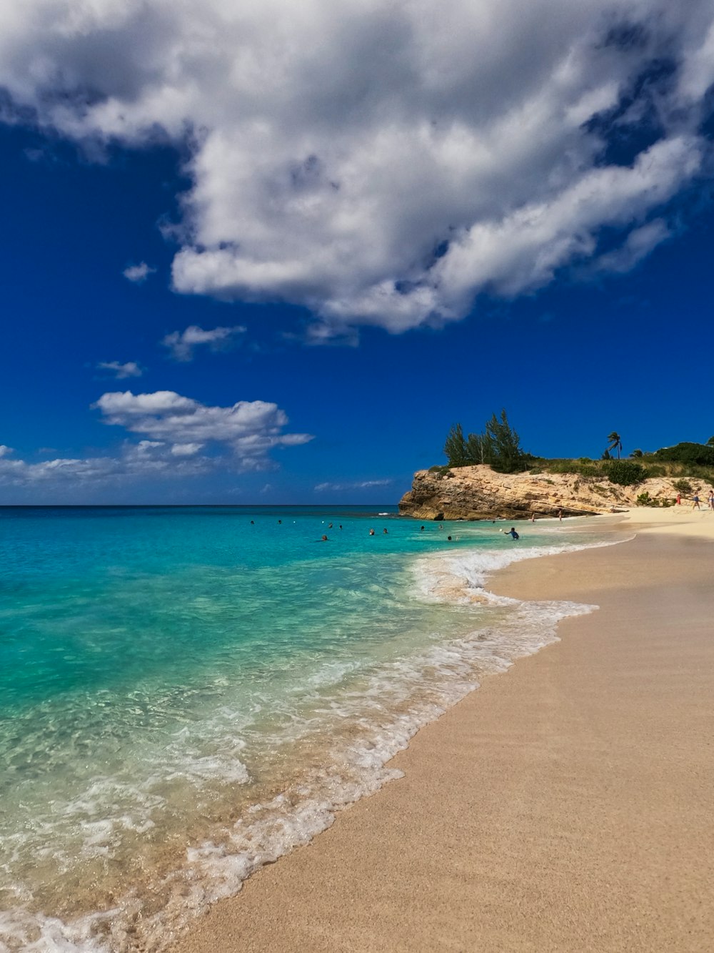 a sandy beach with clear blue water under a cloudy sky