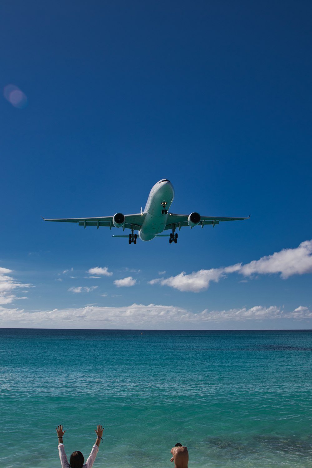 a large jetliner flying over a blue ocean
