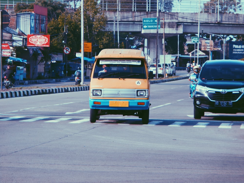 an orange and blue bus driving down a street