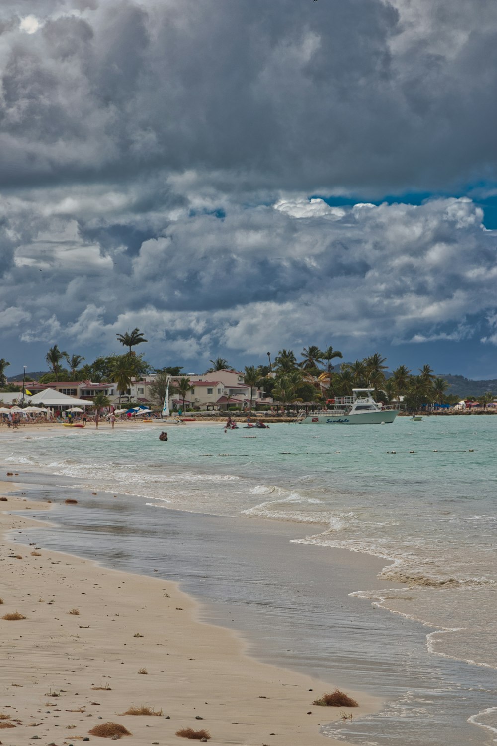 a beach with a few people on it under a cloudy sky