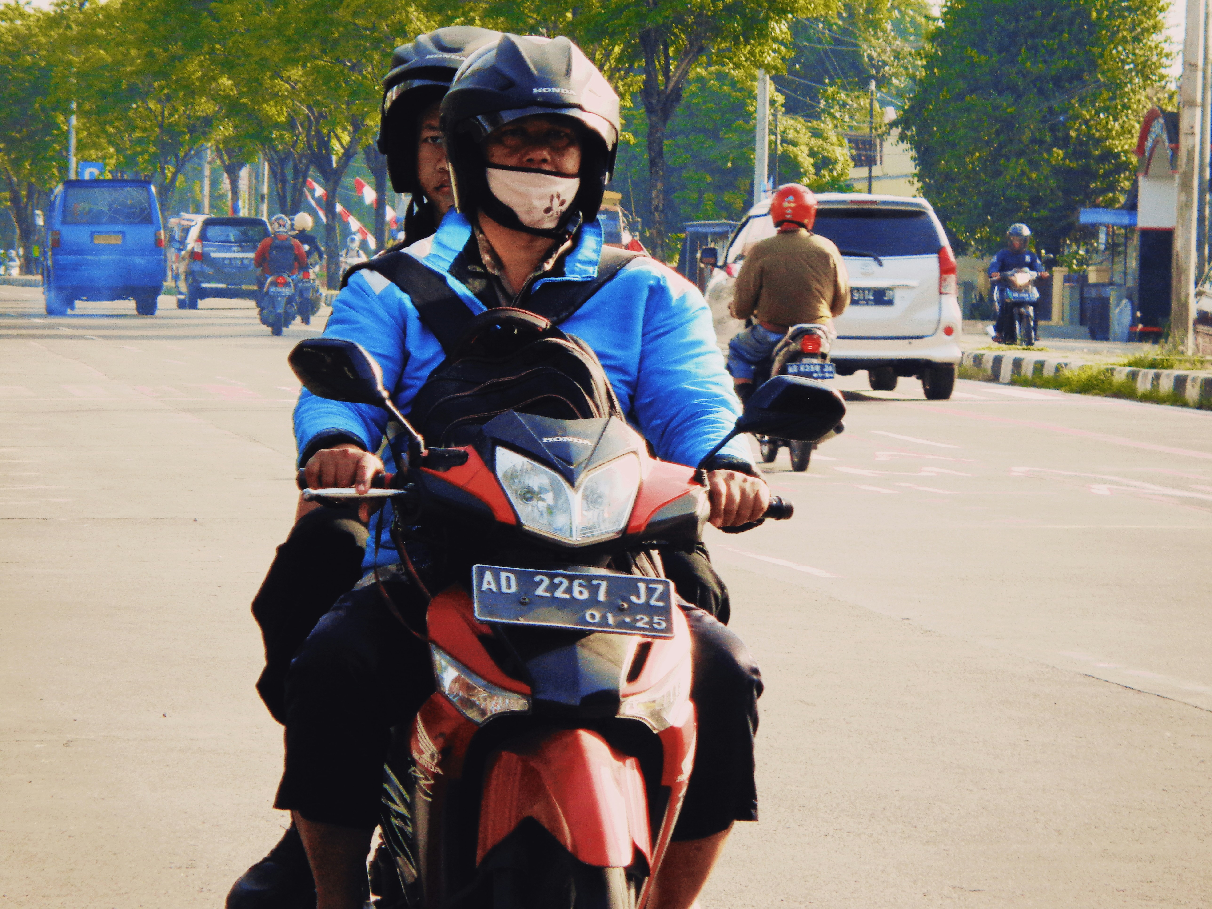 Seorang pria mengendarai sepeda motor di jalan