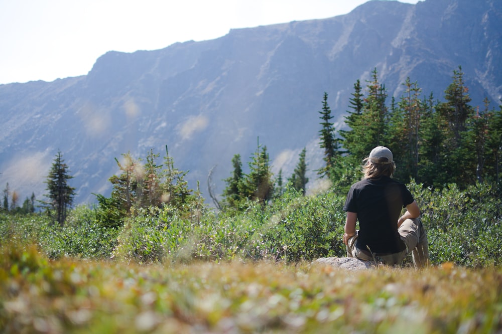 a man sitting on a rock in the mountains