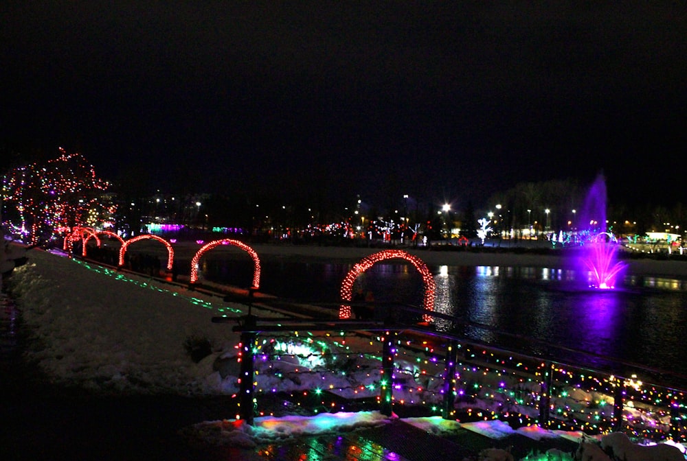 a bridge covered in christmas lights next to a body of water