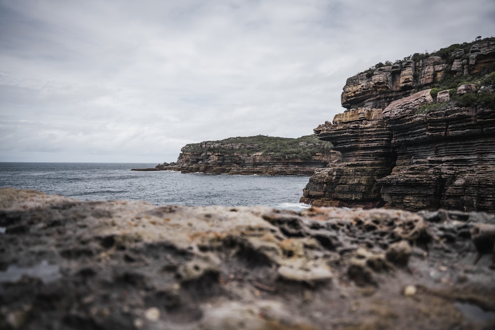 a rocky cliff with a body of water in the background