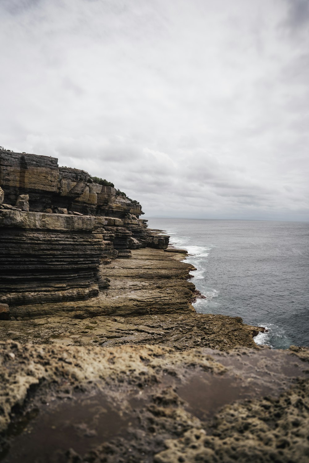 a rocky cliff overlooks the ocean on a cloudy day