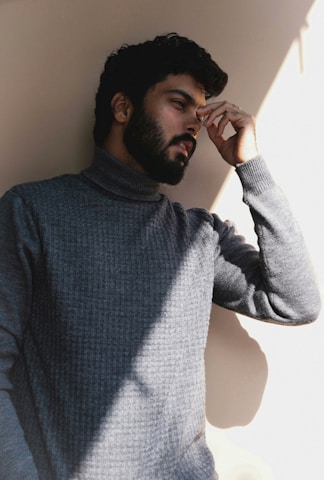 a man with a beard leaning against a wall