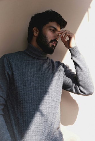 a man with a beard leaning against a wall