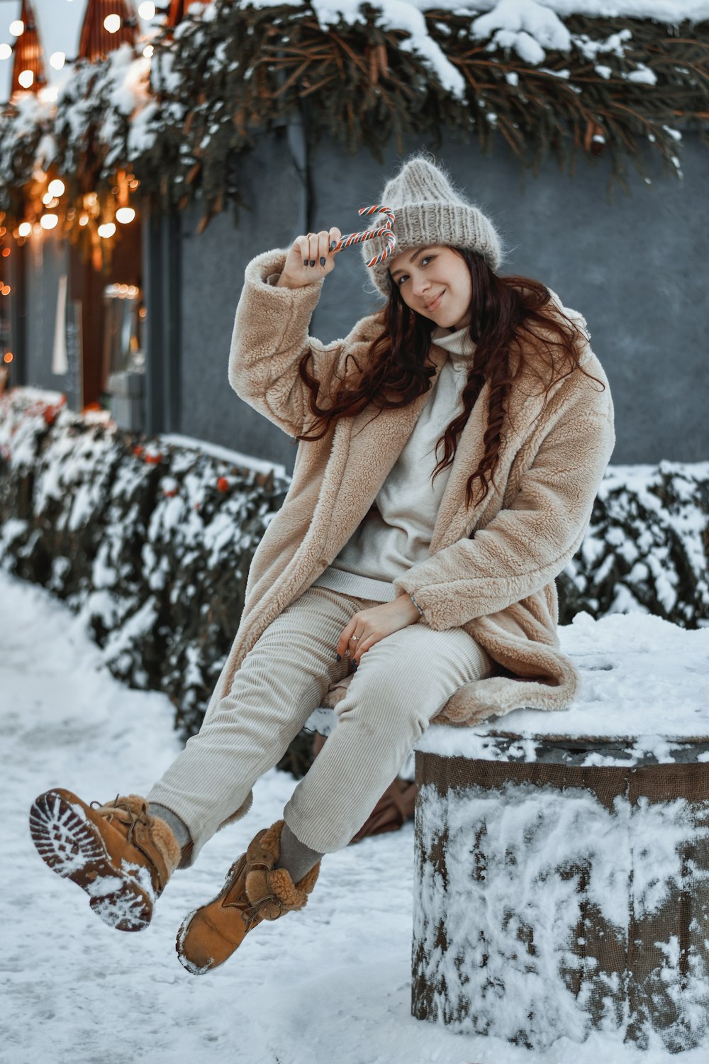 a woman sitting on top of a tree stump in the snow