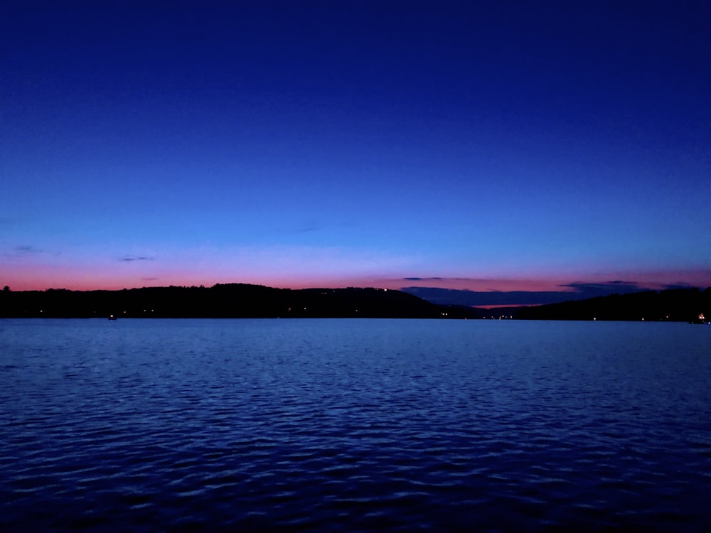 a body of water with a hill in the background