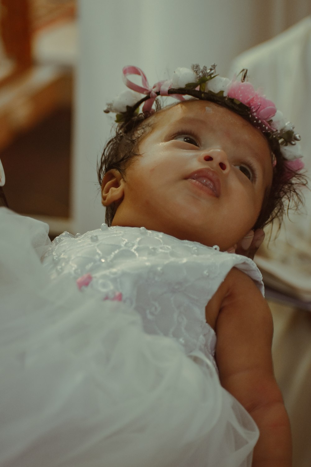 a little girl in a white dress with a flower in her hair