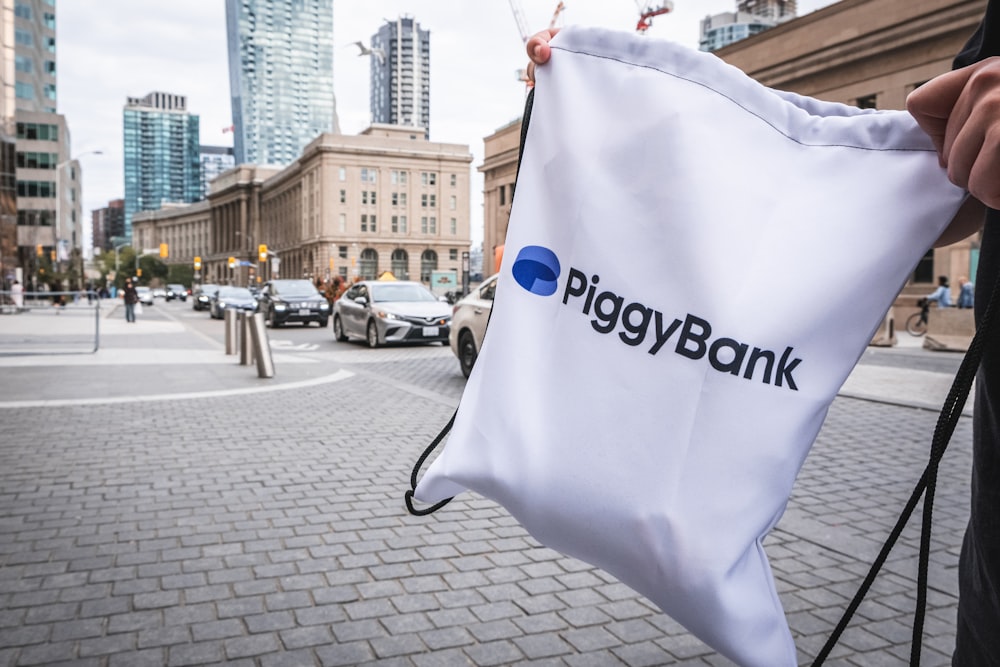 a person holding a bag with a piggy bank logo on it
