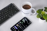 a cell phone sitting next to a cup of coffee