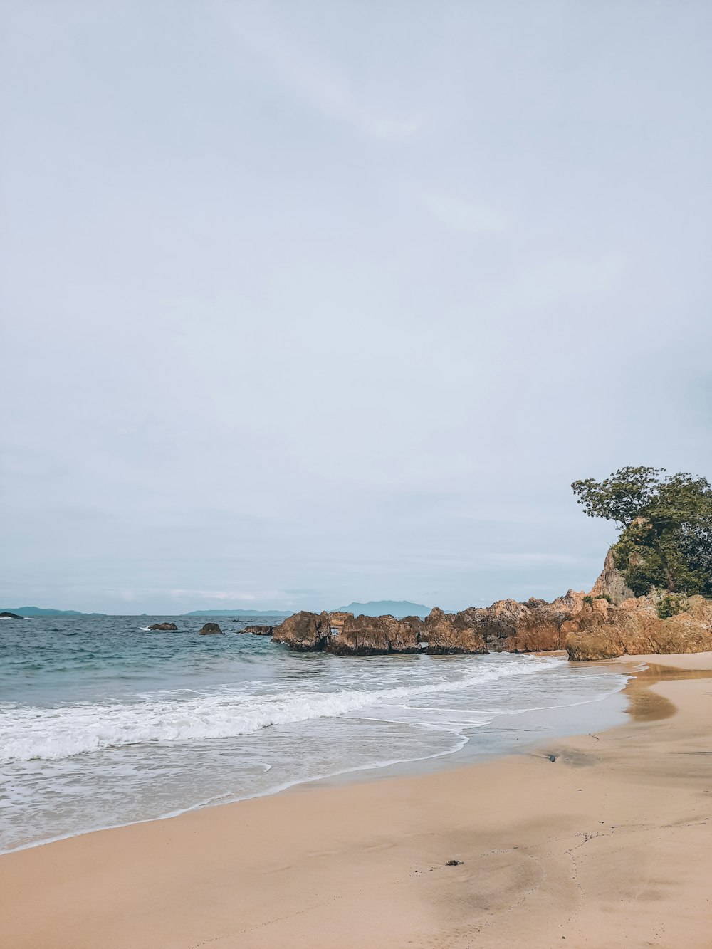 a sandy beach next to the ocean under a cloudy sky