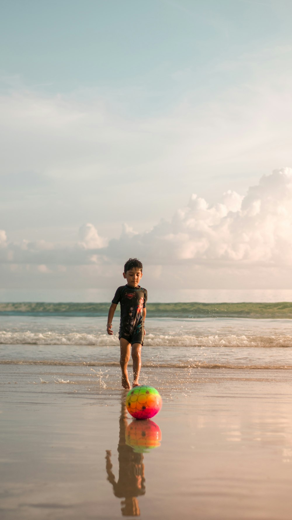 a young boy is playing with a ball on the beach