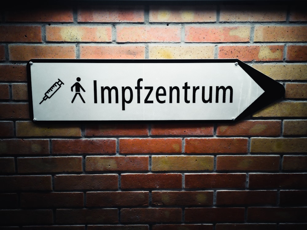 a sign on a brick wall points to the word impfuentrum