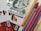 A selection of various colored markers and pens is arranged next to a stack of ten thousand Hungarian forint banknotes. Several credit cards with Visa logos are visible, along with envelopes featuring orange, black, and white chevron patterns.