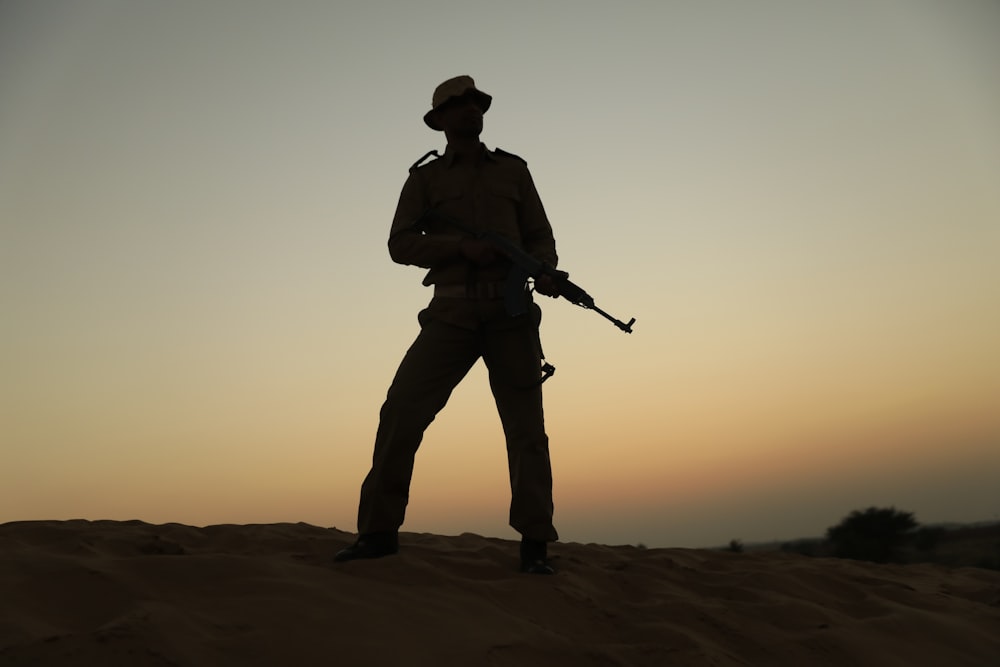 Una silueta de un hombre sosteniendo un rifle en el desierto