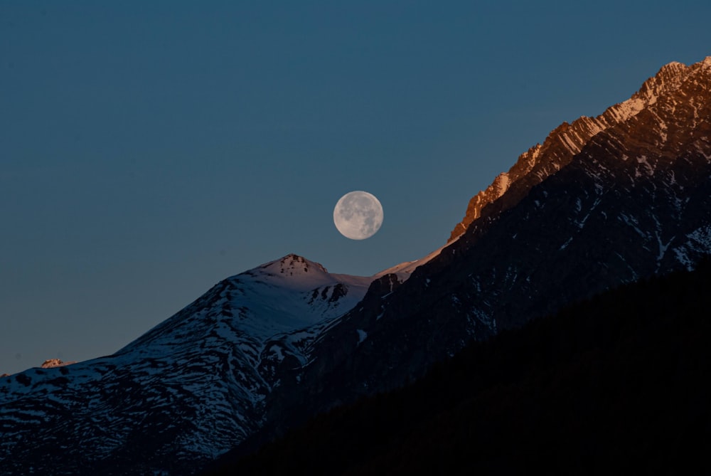 Une pleine lune se levant sur une chaîne de montagnes