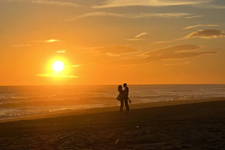 a couple of people standing on top of a sandy beach