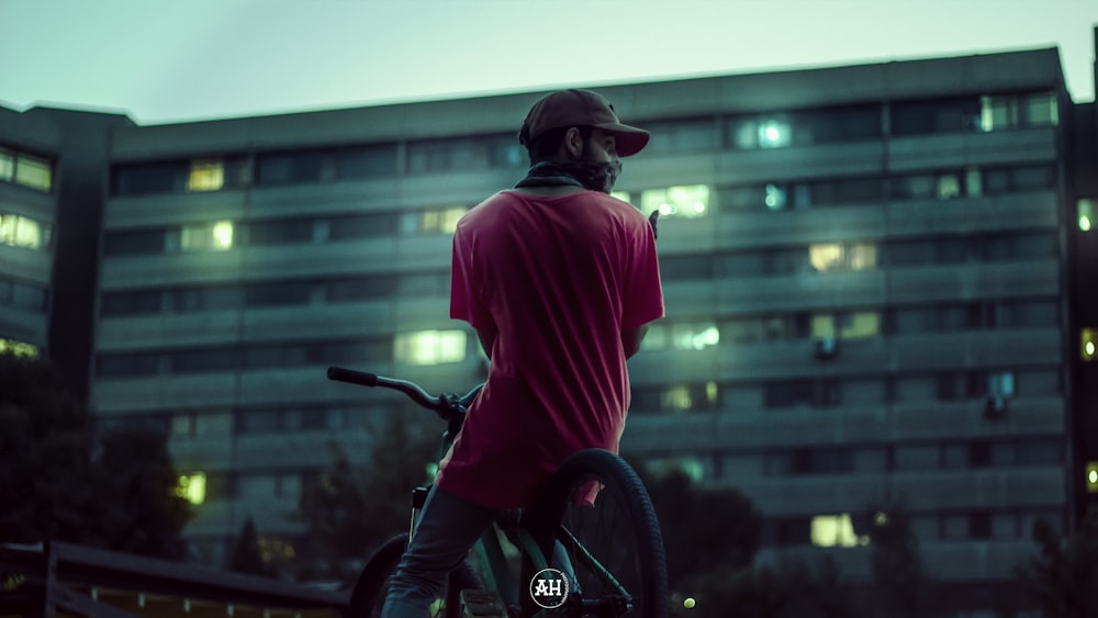 a man riding a bike in front of a tall building