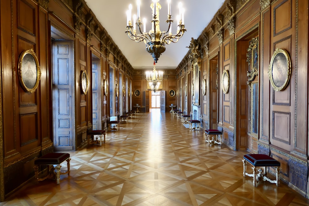 a long hallway with a chandelier and chairs