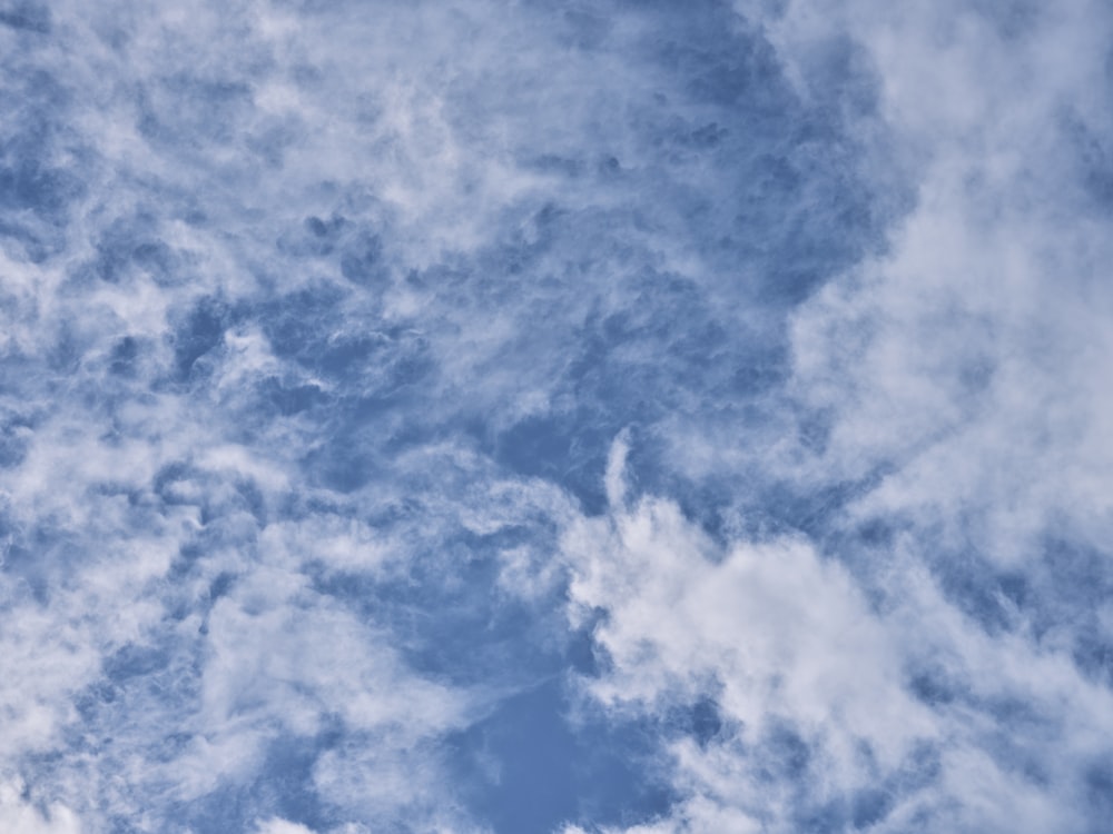 a plane flying through a cloudy blue sky