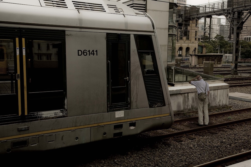 a man standing next to a train on a train track