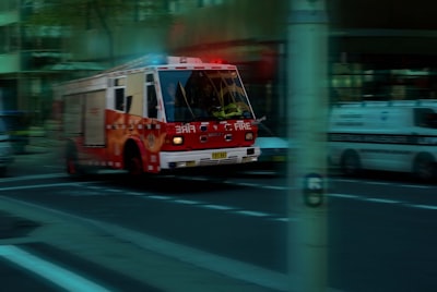 a red fire truck driving down a street next to a tall building