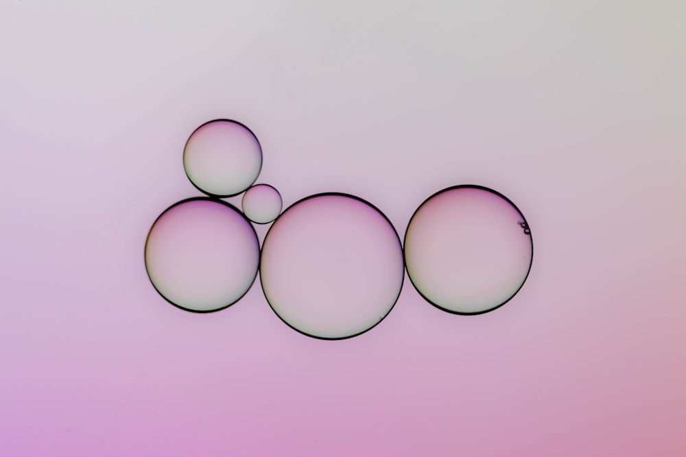a group of three bubbles sitting on top of a pink and purple background