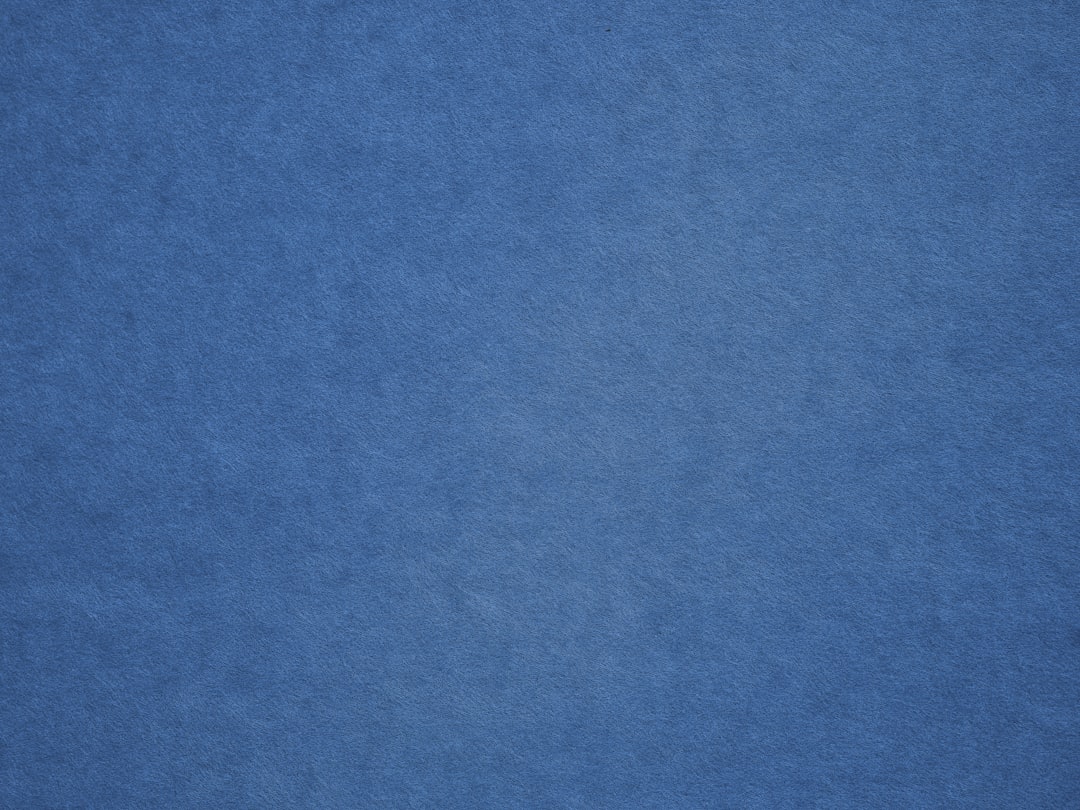 an airplane is flying in the blue sky, texture of a synthetic blue carpet