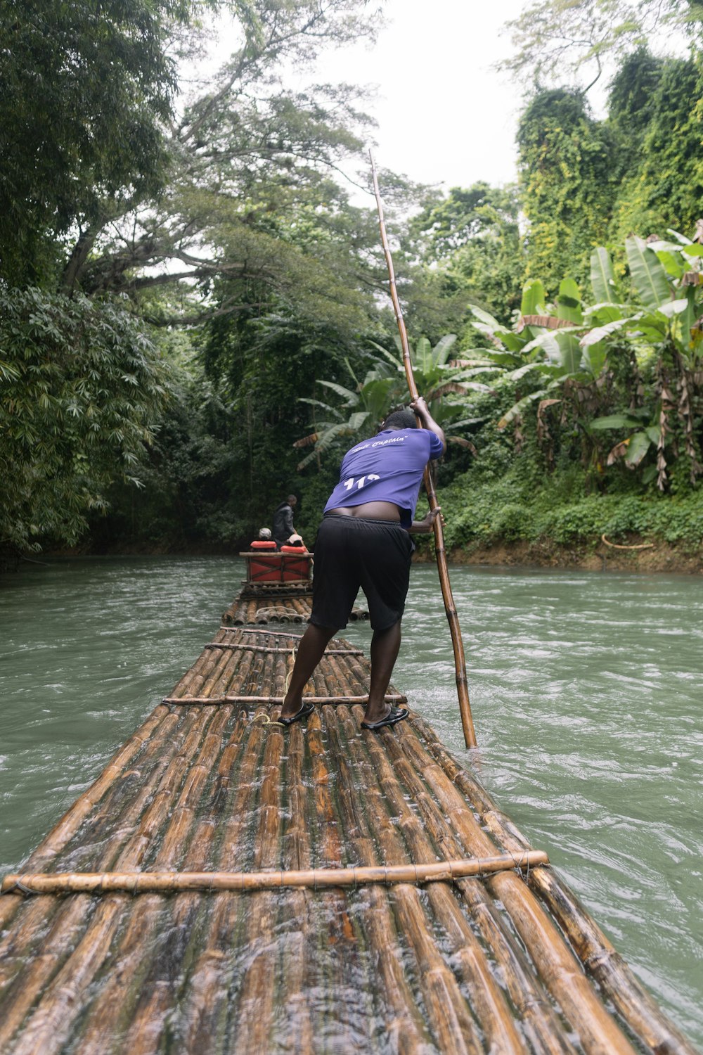 a person standing on a bamboo raft in a river