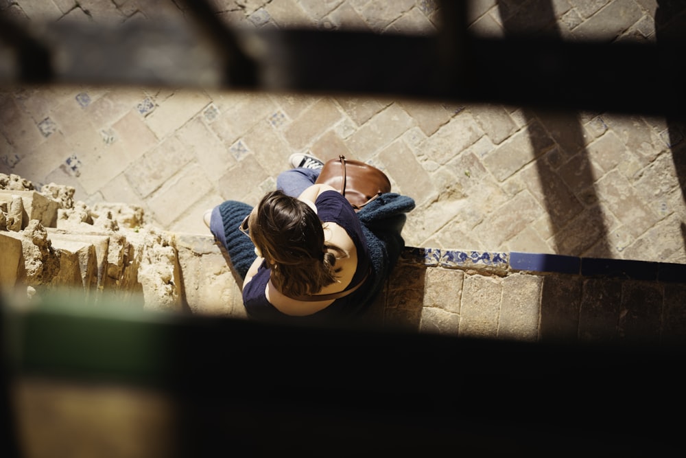 a woman sitting on a ledge looking down